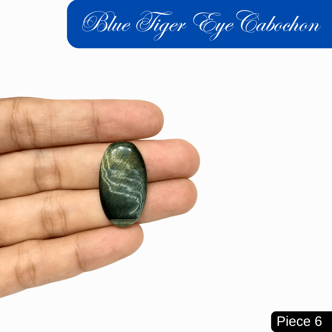 Hand holding a blue tiger eye cabochon with chatoyant bands, known for its calming energy and protective properties.