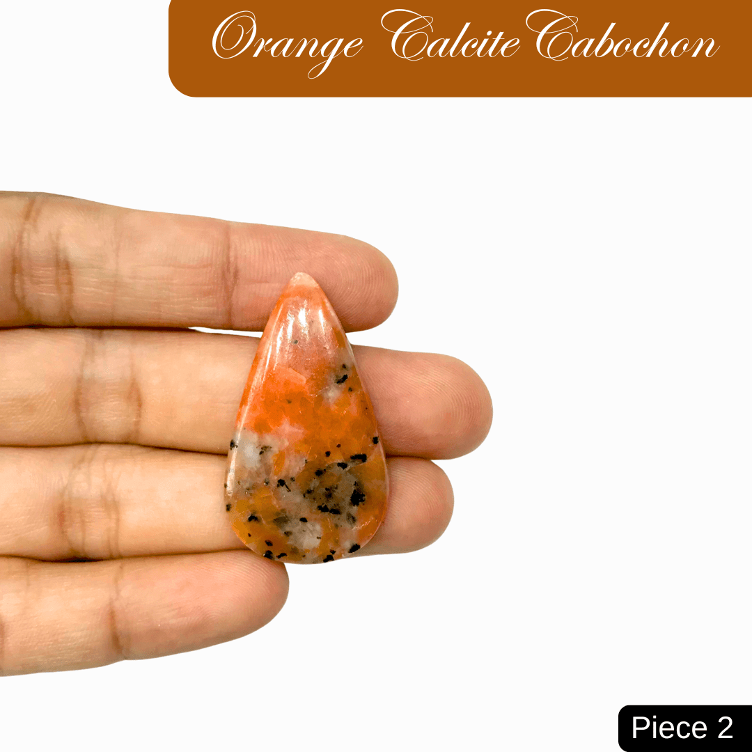 Hand holding tear-shaped Orange Calcite cabochon, known for creativity and joy, with vibrant hues and unique patterns.