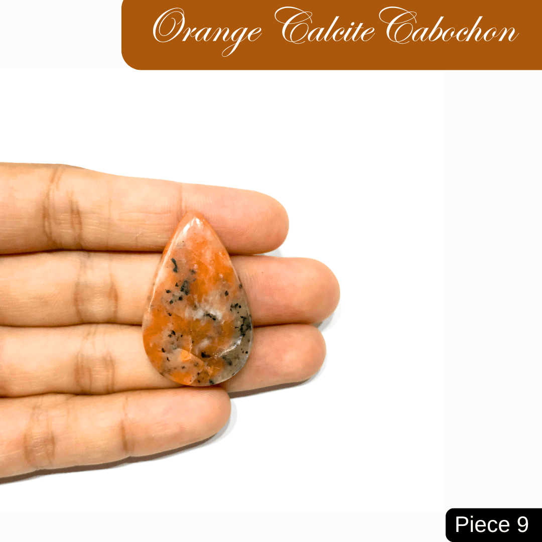 Teardrop-shaped Orange Calcite cabochon against a white background, held in hand, showcasing its vibrant color and natural patterns.