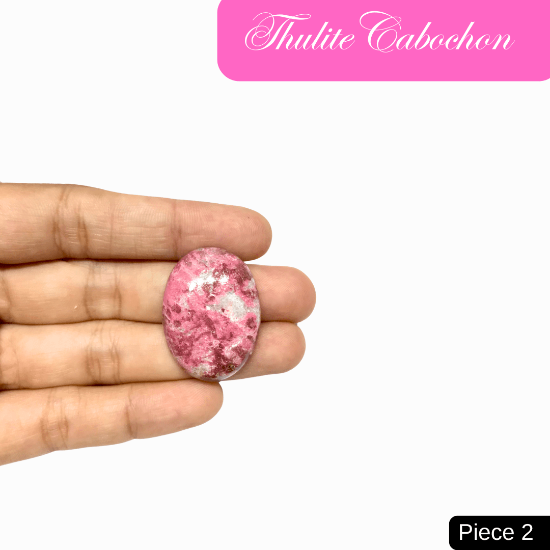 Hand holding Thulite Cabochon, a pink stone known for love and emotional healing.