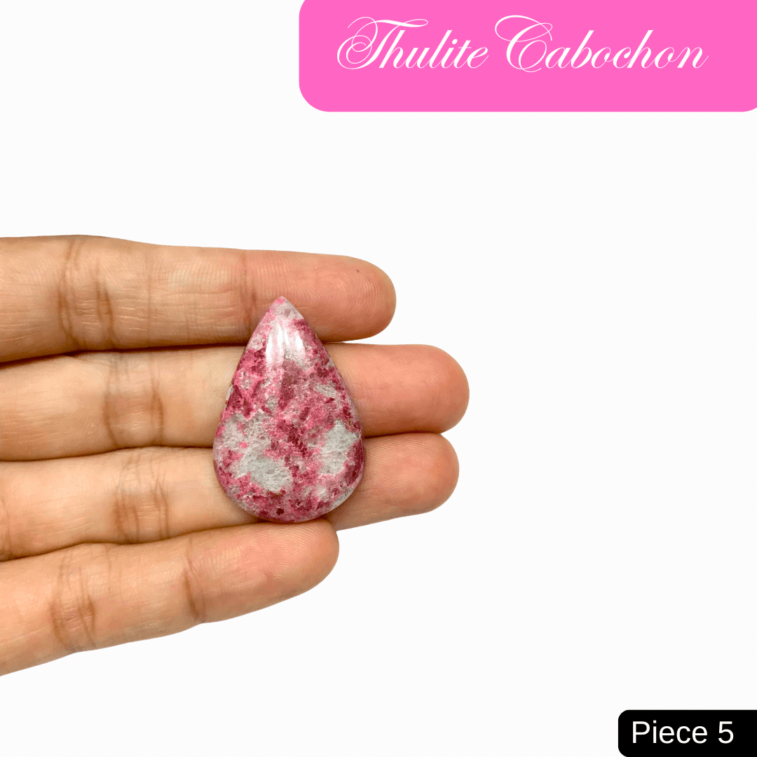 Hand holding a pink Thulite cabochon, known for its love and healing properties, enhancing emotional well-being and heart-centered communication.