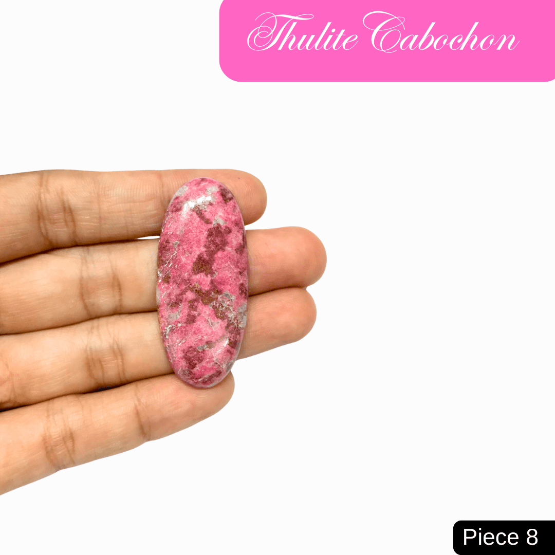 Hand holding Thulite cabochon with pink hues, promoting love, vitality, and emotional healing. Ideal for Heart Chakra support.