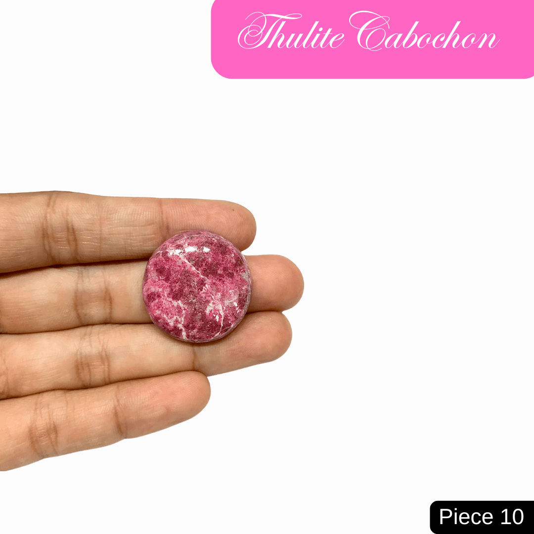 Thulite Cabochon in hand, showcasing its pink shades and round shape, symbolizing love, vitality, and heart-centered communication.