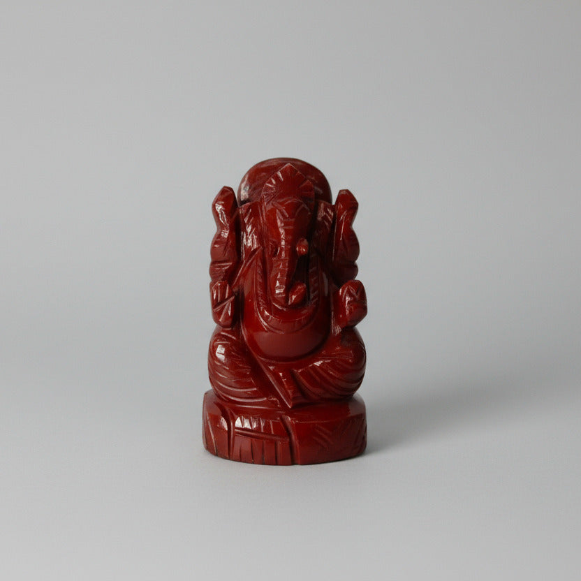 Red stone statue of a deity on a white background