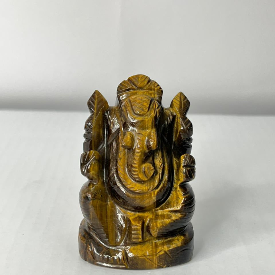 Tiger's eye stone sculpture of a deity on a white background