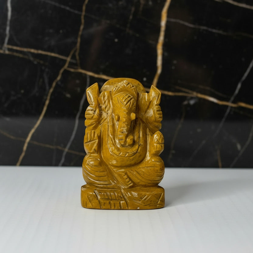 Brown stone sculpture of a deity on a white background
 Aeora rocks yellow jasper ganesha