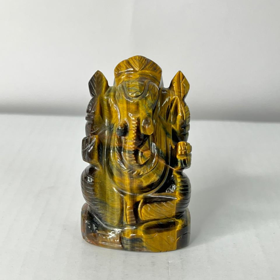Tiger's eye crystal sculpture of a deity on a white background