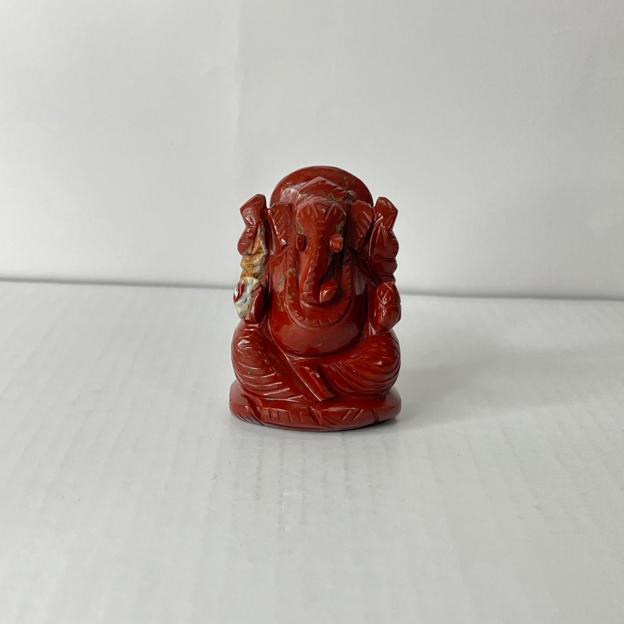 Red stone sculpture of a seated figure on a white background