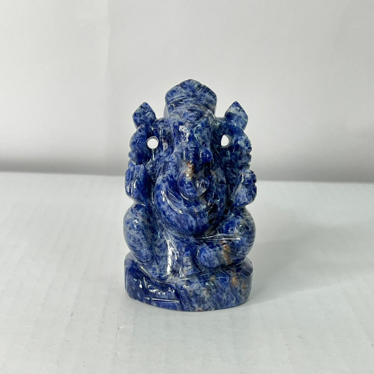 Blue stone sculpture of a deity on a white background