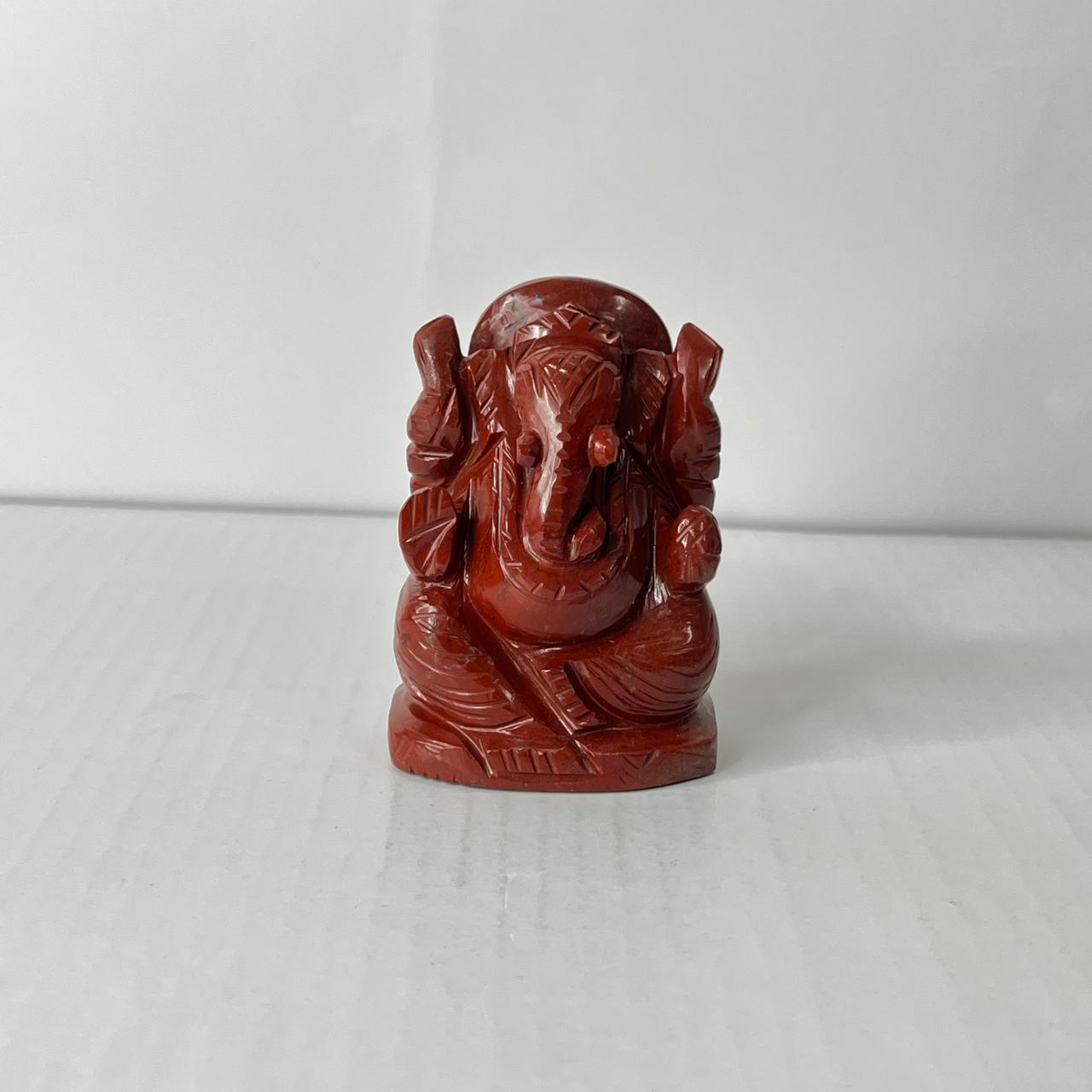 Red stone sculpture of a deity on a white background