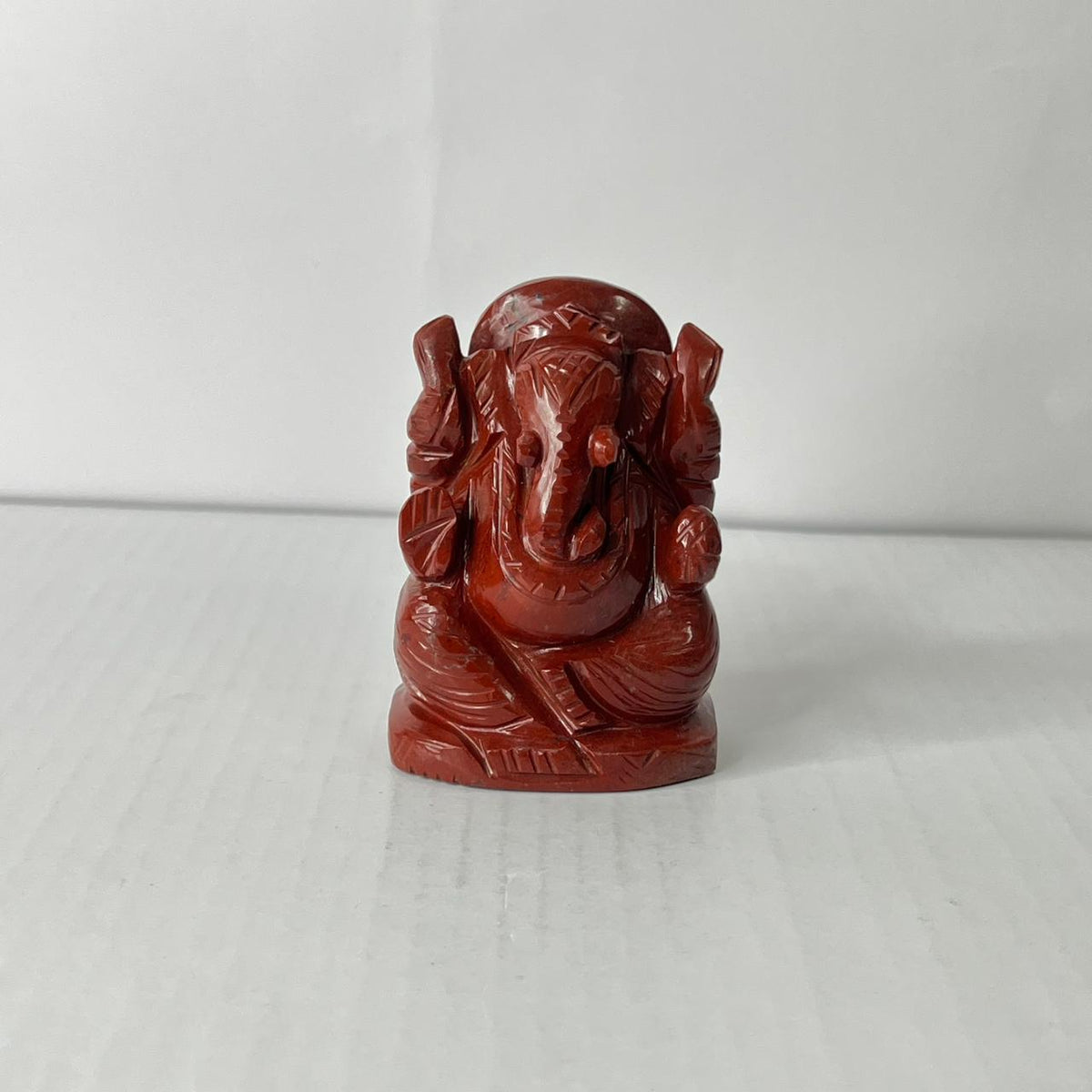 Red stone sculpture of a deity on a white background