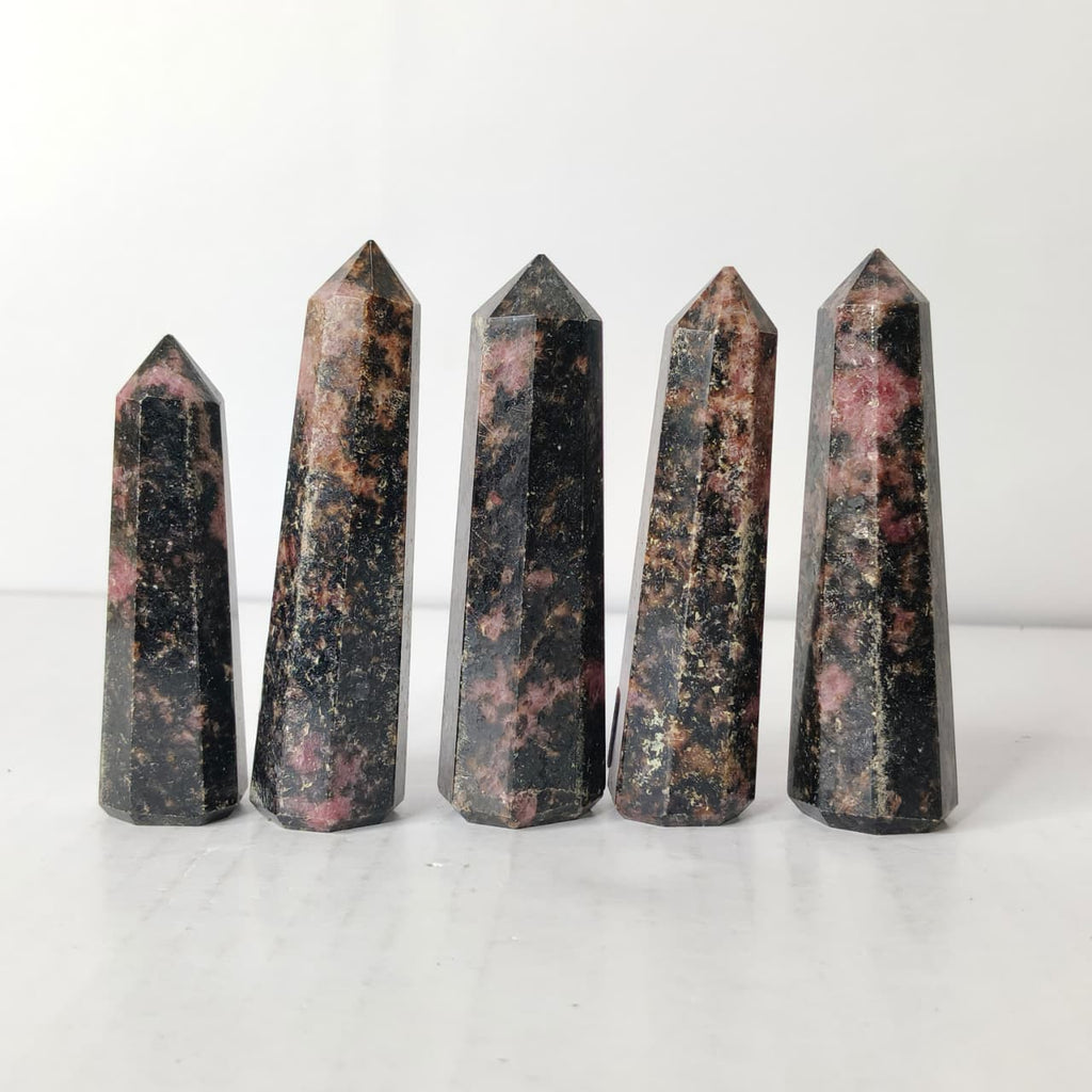 Five polished crystal obelisks on a white background