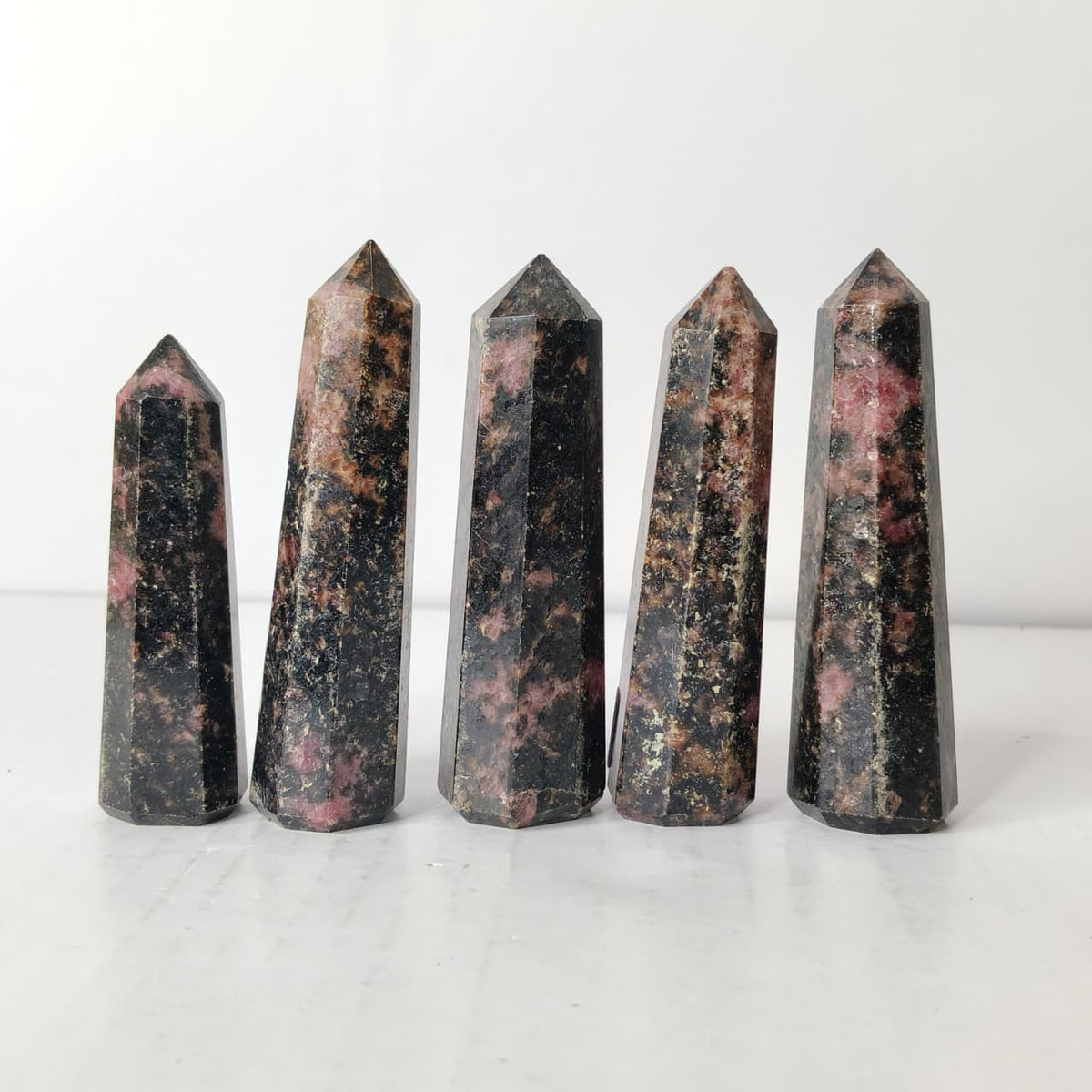 Five polished crystal obelisks on a white background