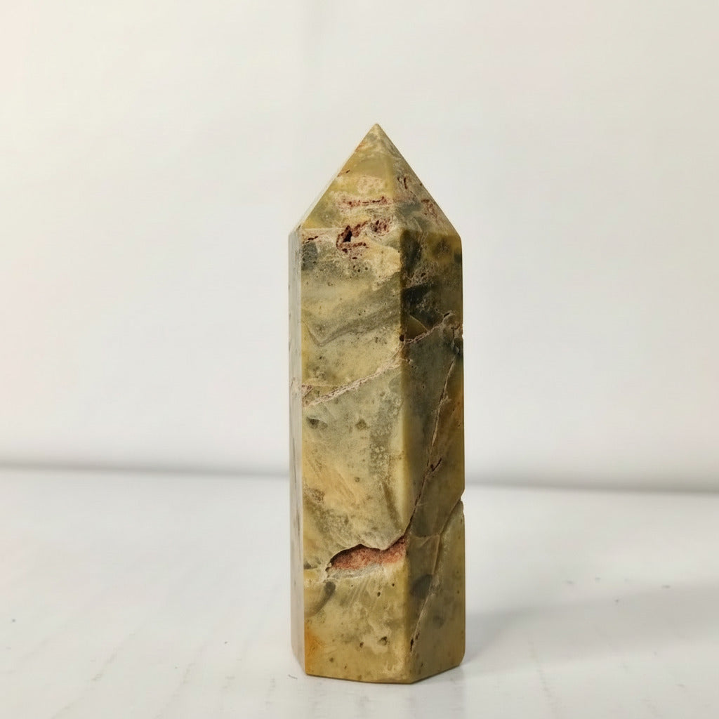 Marble-like stone obelisk on a white background Crazy lace Agate point tower