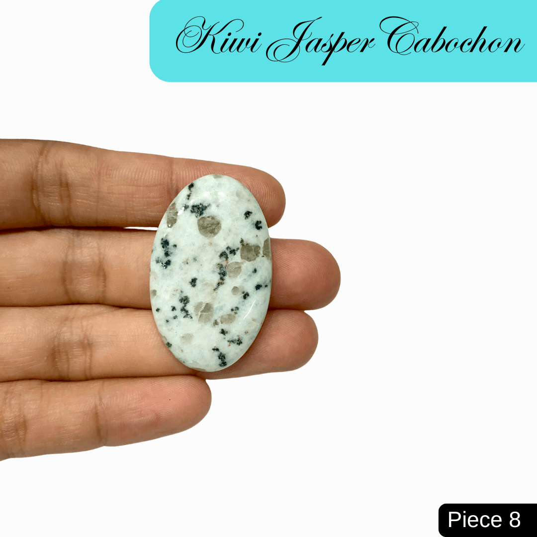 Hand holding a Kiwi Jasper cabochon with green hue and black speckles, symbolizing tranquility and emotional strength.