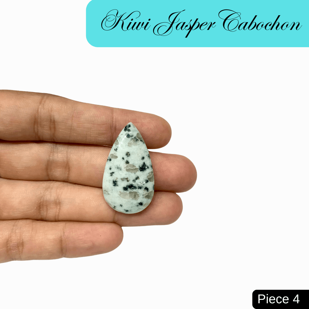 Kiwi Jasper Cabochon in hand, teardrop shape, soft green color with black speckles, known for emotional balance and spiritual cleansing.