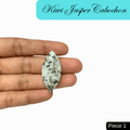 Person holding a green and black speckled Kiwi Jasper cabochon, known for tranquility and emotional strength. Piece 1.