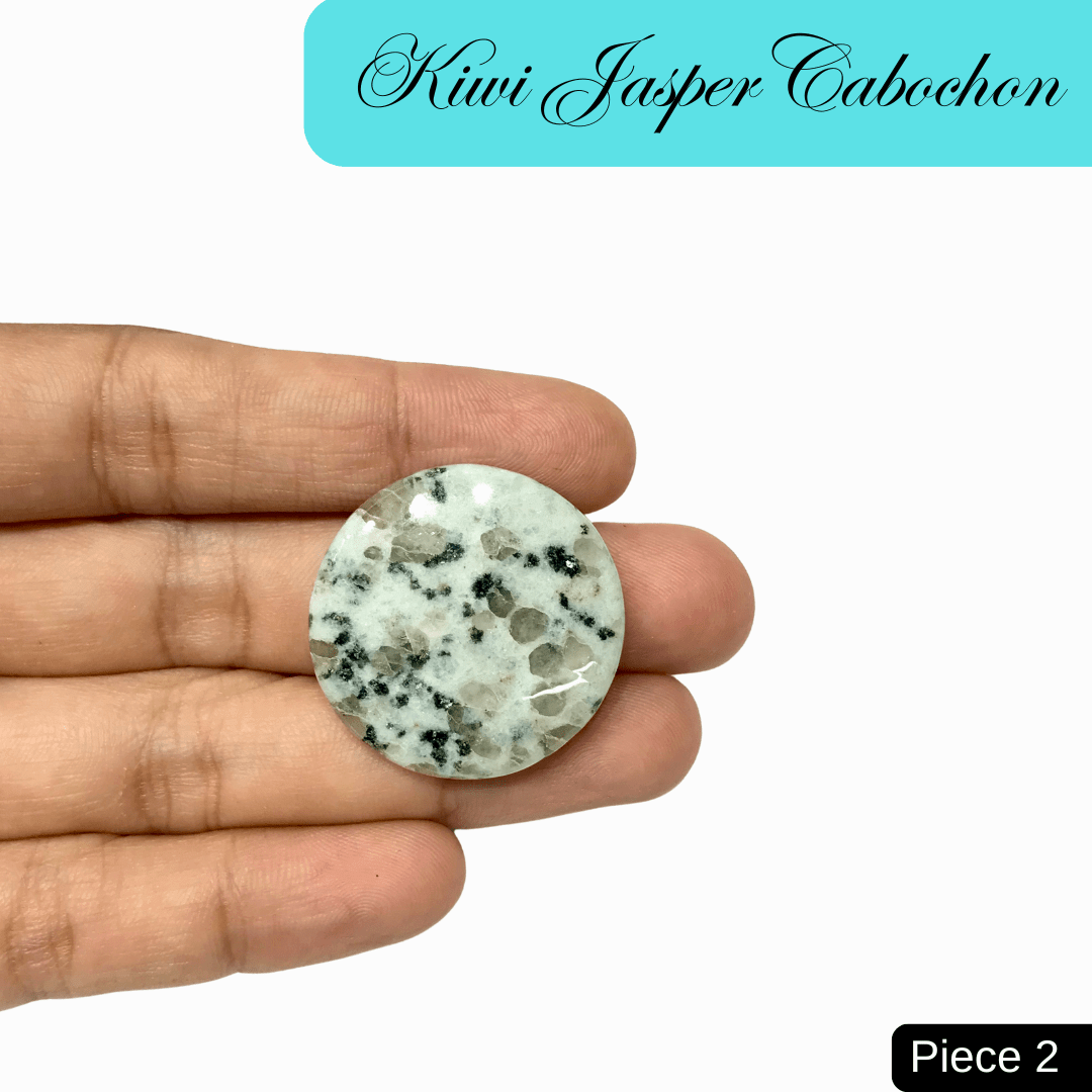 Hand holding a round Kiwi Jasper Cabochon with green, black, and cream speckles, offering tranquility and emotional strength.