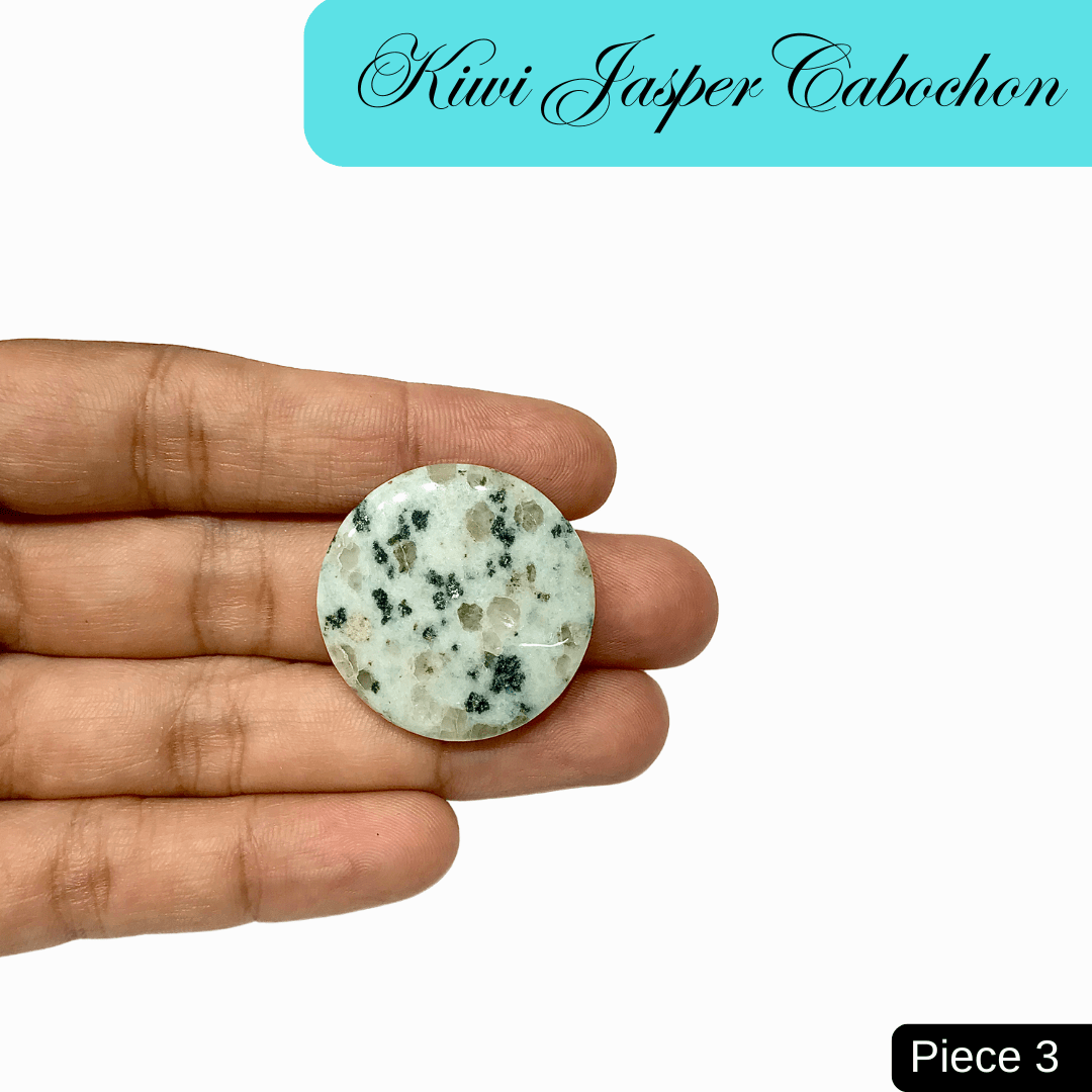 Hand holding a polished Kiwi Jasper cabochon, showcasing its green hue with black and cream speckles, symbolizing tranquility and balance.