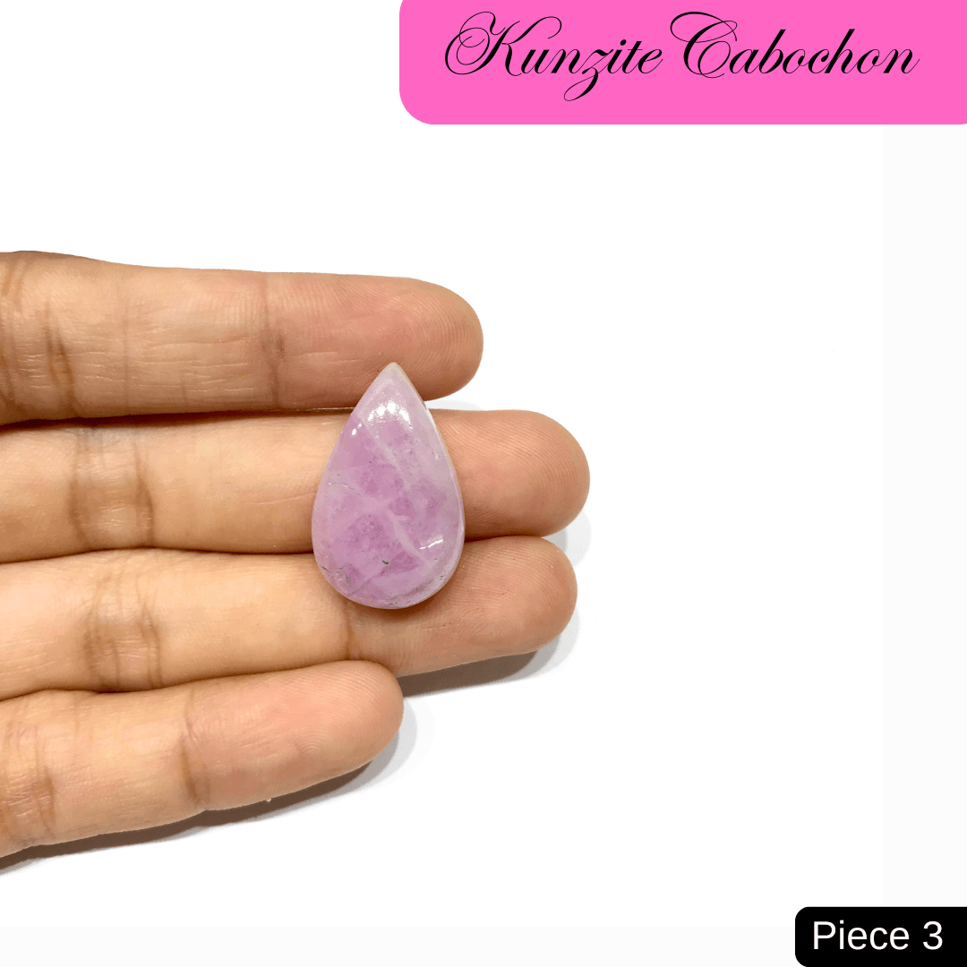 Hand holding a teardrop-shaped pale pink Kunzite cabochon, known for its emotional healing and spiritual awakening properties.