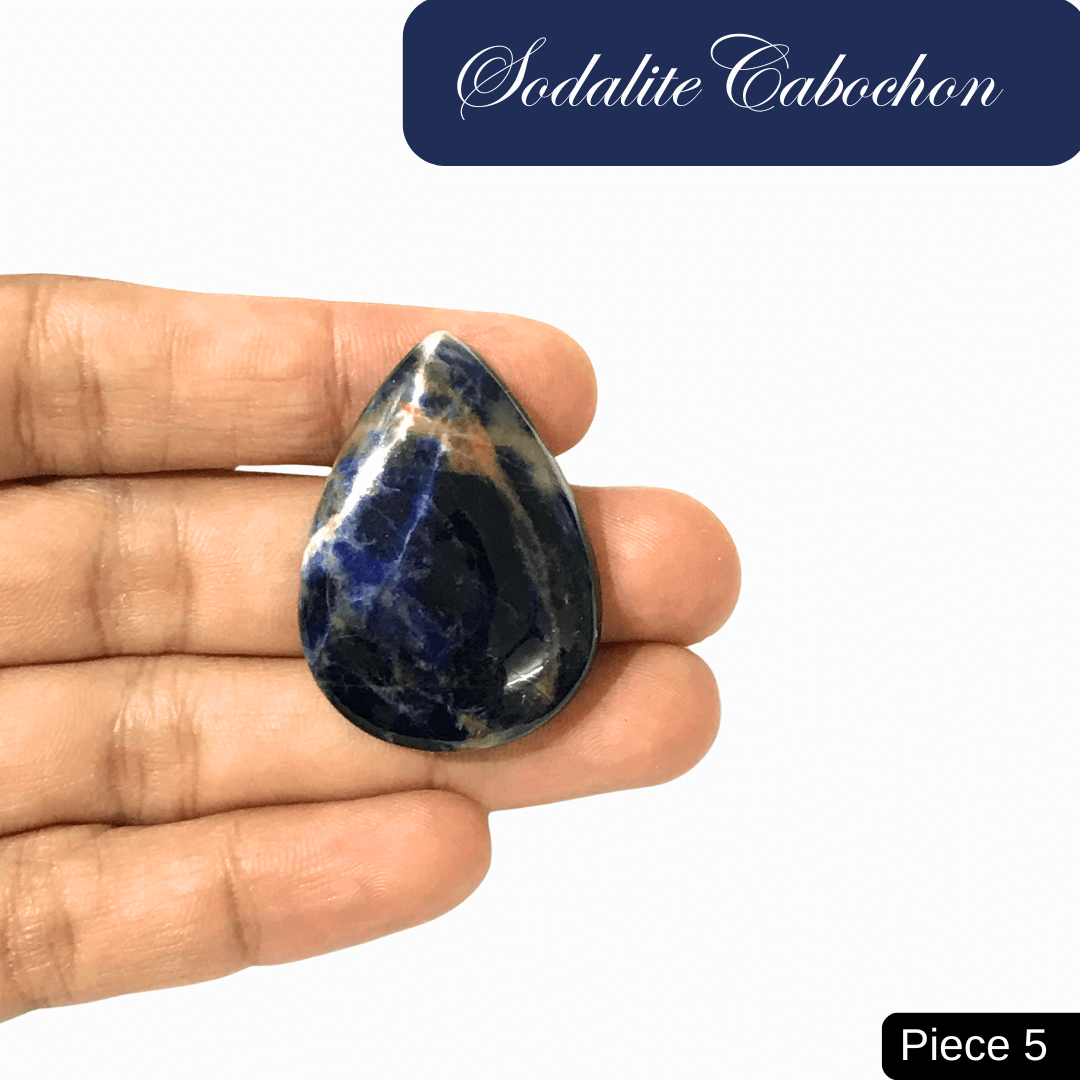 Hand holding a teardrop-shaped sodalite cabochon, featuring rich blue tones with white calcite veins, enhancing intuition and clarity.