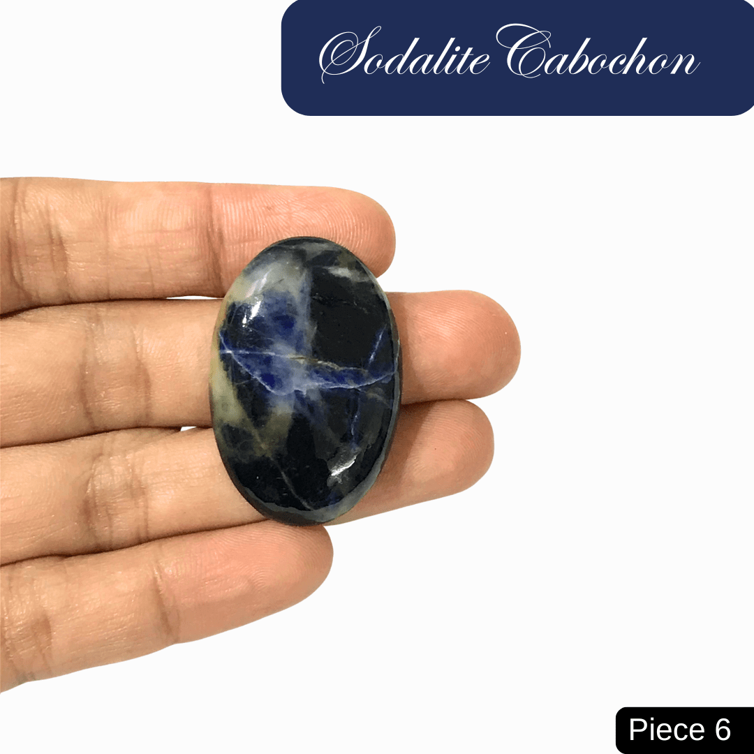 Hand holding Sodalite cabochon with deep blue and white calcite veins, symbolizing truth, intuition, and mental clarity.