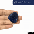 Sodalite cabochon in hand, showcasing rich blue tones and white calcite veins. Promotes truth, intuition, and mental clarity.