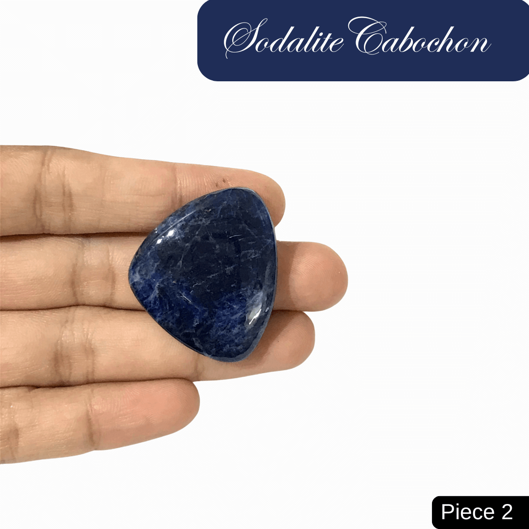 Sodalite cabochon in hand, showcasing rich blue tones and white calcite veins. Promotes truth, intuition, and mental clarity.