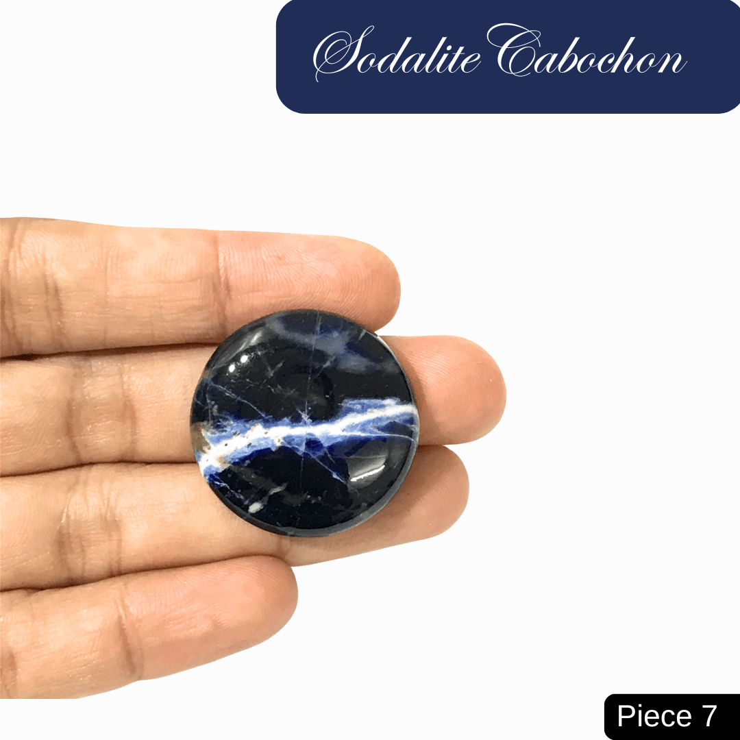 Round sodalite cabochon with blue and white veining, held in a hand, symbolizing truth and intuition. Ideal for mental clarity.