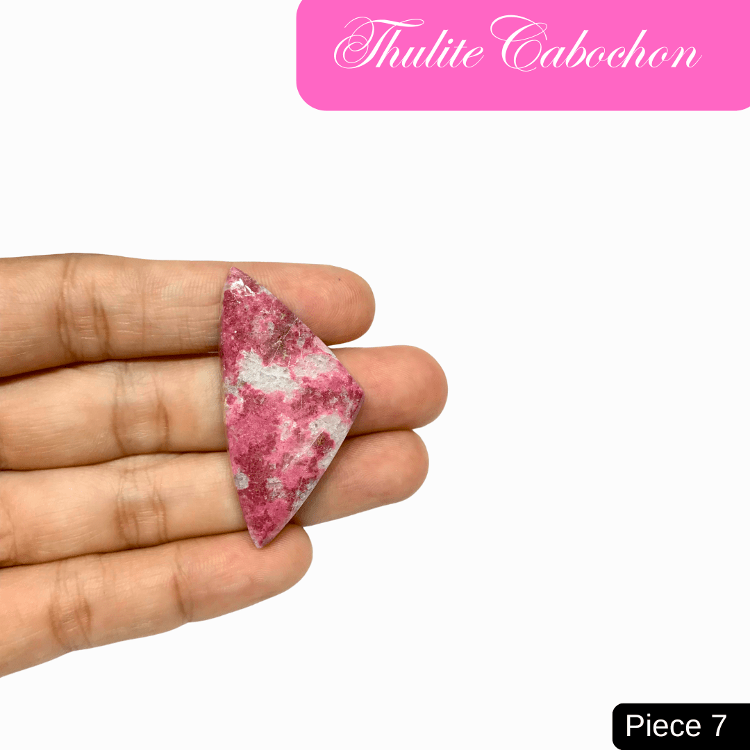 Hand holding a pink Thulite cabochon, showcasing its vibrant raspberry hues and unique patterns, promoting love and emotional healing.