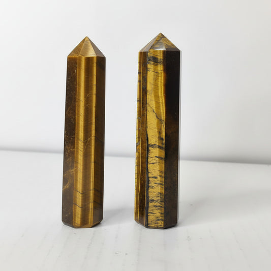 Two tiger eye crystal points on a white background