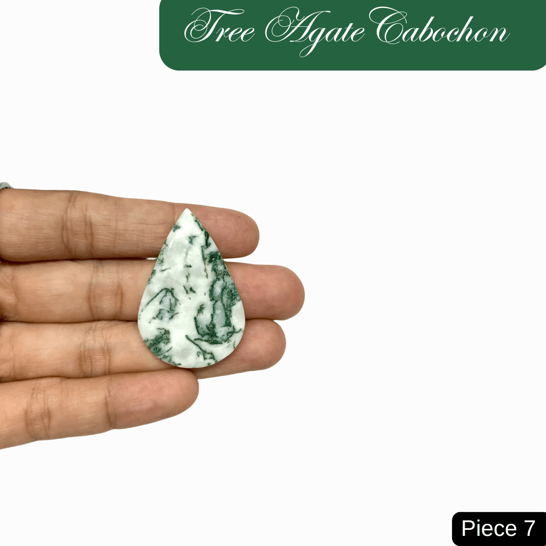 Hand holding a pear-shaped Tree Agate cabochon, showcasing its soothing green and white marbled patterns and connection to nature.